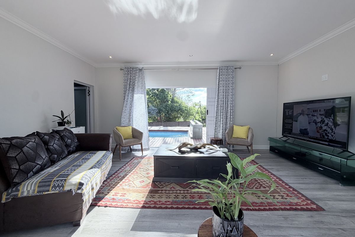 Spacious living room featuring modern laminate flooring, recessed lighting, and large sliding glass doors that open directly onto the outdoor pool area.