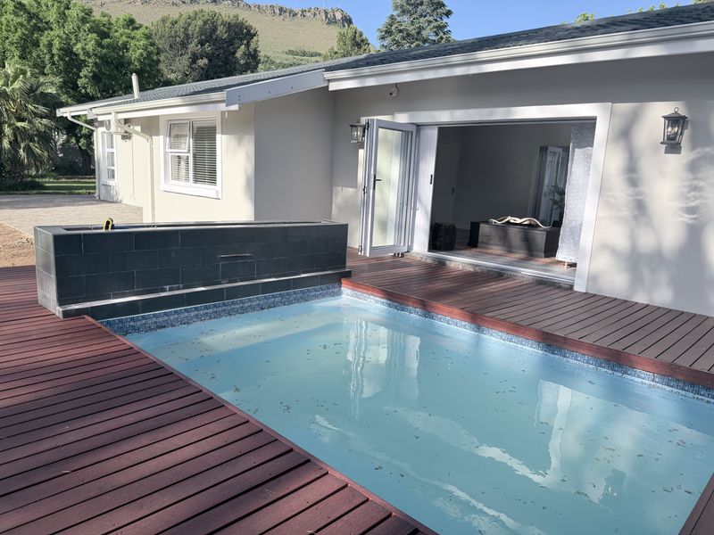 Outdoor pool area featuring timber decking, a tiled water feature, and direct access to the interior through bi-fold doors.