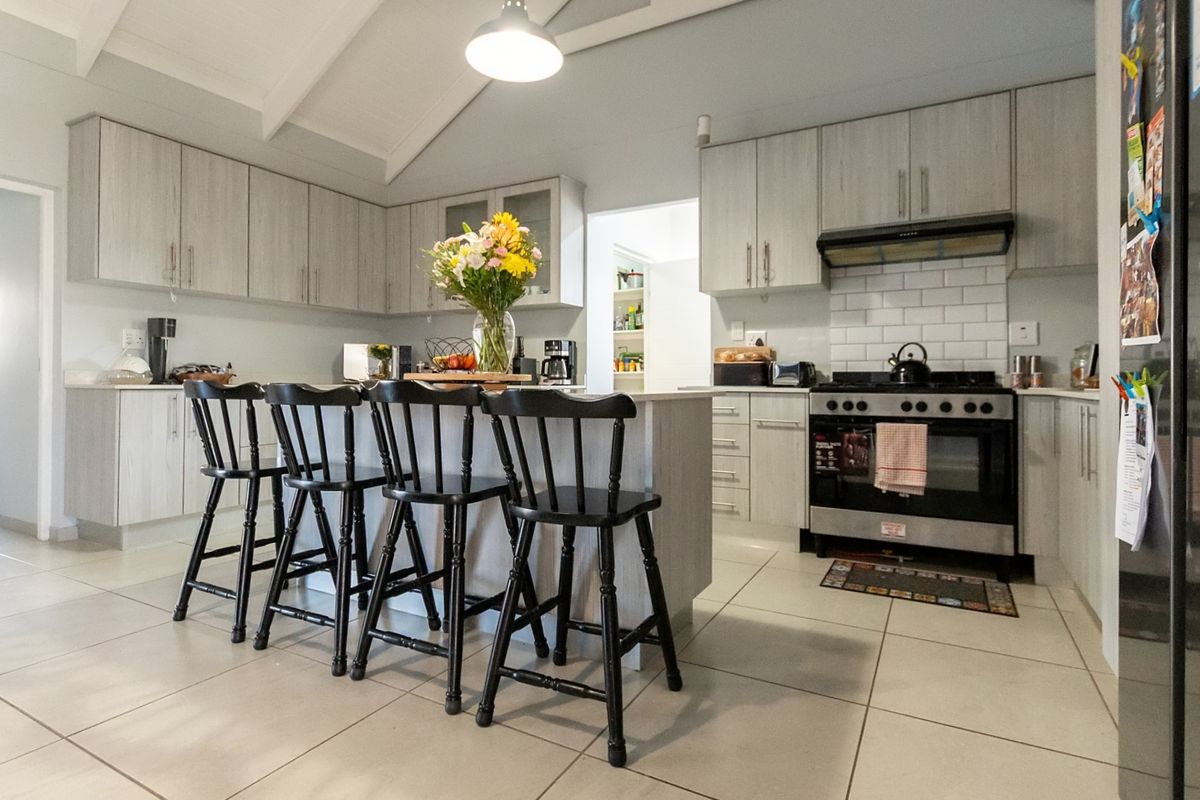 Modern kitchen featuring light wood-toned cabinetry, a central island with breakfast bar seating, subway tile backsplash, and a stainless steel gas stove.