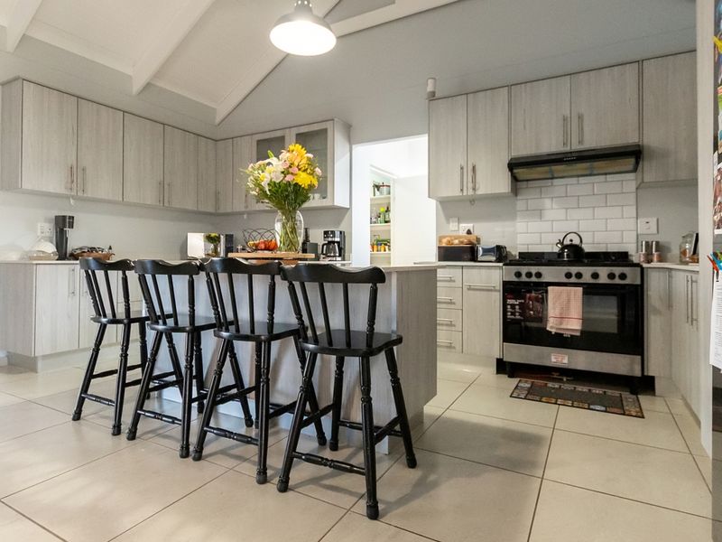 Modern kitchen featuring light wood-toned cabinetry, a central island with breakfast bar seating, subway tile backsplash, and a stainless steel gas stove.