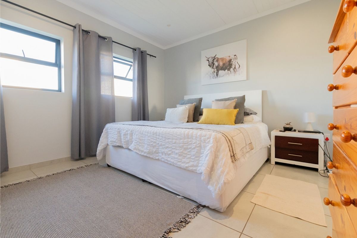 A well-lit bedroom featuring neutral wall tones, tiled flooring, and functional top-hung windows, providing a clean and comfortable living space.