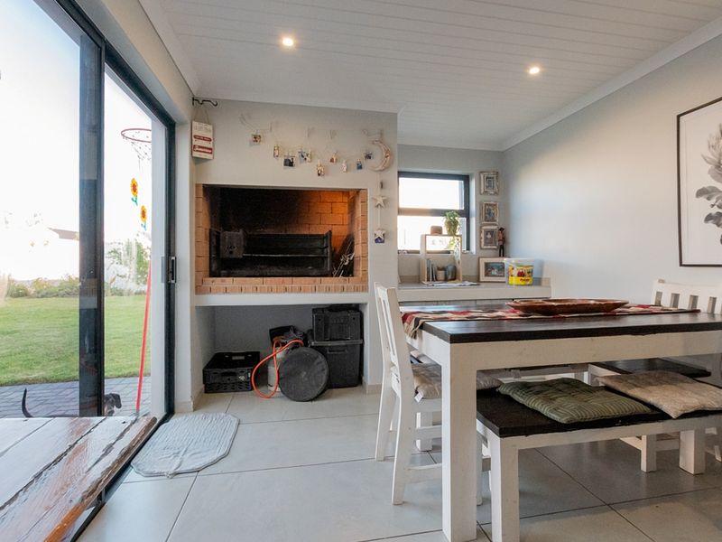 Enclosed patio area featuring a built-in brick braai, large sliding glass doors providing garden access, and modern tiled flooring.