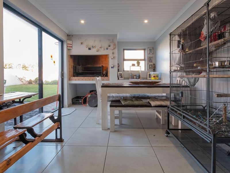 Covered patio area featuring a built-in braai, tiled flooring, and large sliding glass doors providing direct access to the garden.