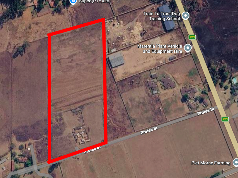 Aerial view of a large, rectangular vacant residential plot with clear boundary markings, situated near local infrastructure and road access.