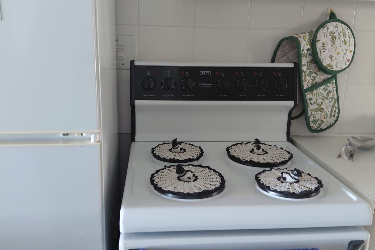 A functional kitchen area featuring a white freestanding stove, white cabinetry, and a tiled backsplash.