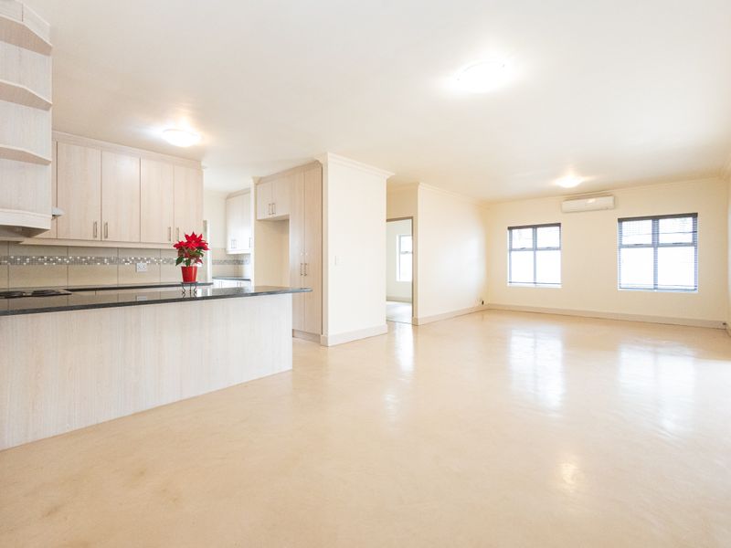 Spacious open-plan living area featuring a modern kitchen with granite countertops, built-in cabinetry, and a neutral tiled floor throughout.