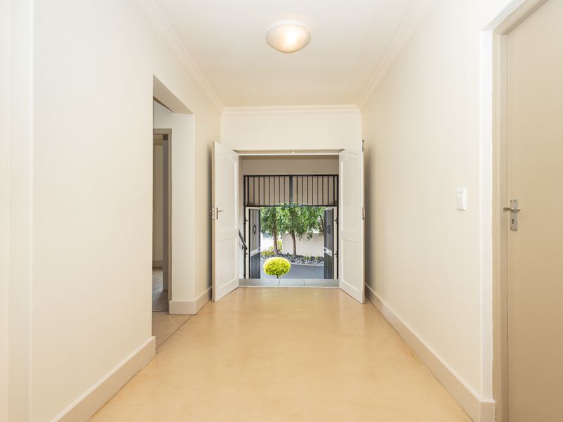 A bright and spacious entrance hall featuring double doors with a security gate, leading to an outdoor area.