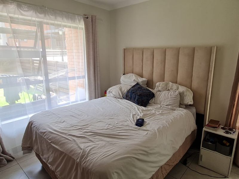 A bedroom featuring tiled flooring, a large window providing natural light, and a built-in wardrobe.