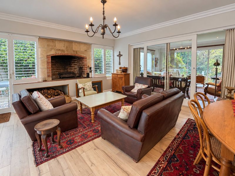 A cozy living room featuring a prominent brick and stone fireplace with integrated wood storage, light wood-look flooring, and large sliding doors to the patio.