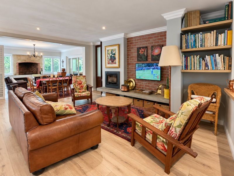 Spacious open-plan living and dining area featuring a characterful exposed brick fireplace, built-in shelving, and modern laminate flooring throughout.