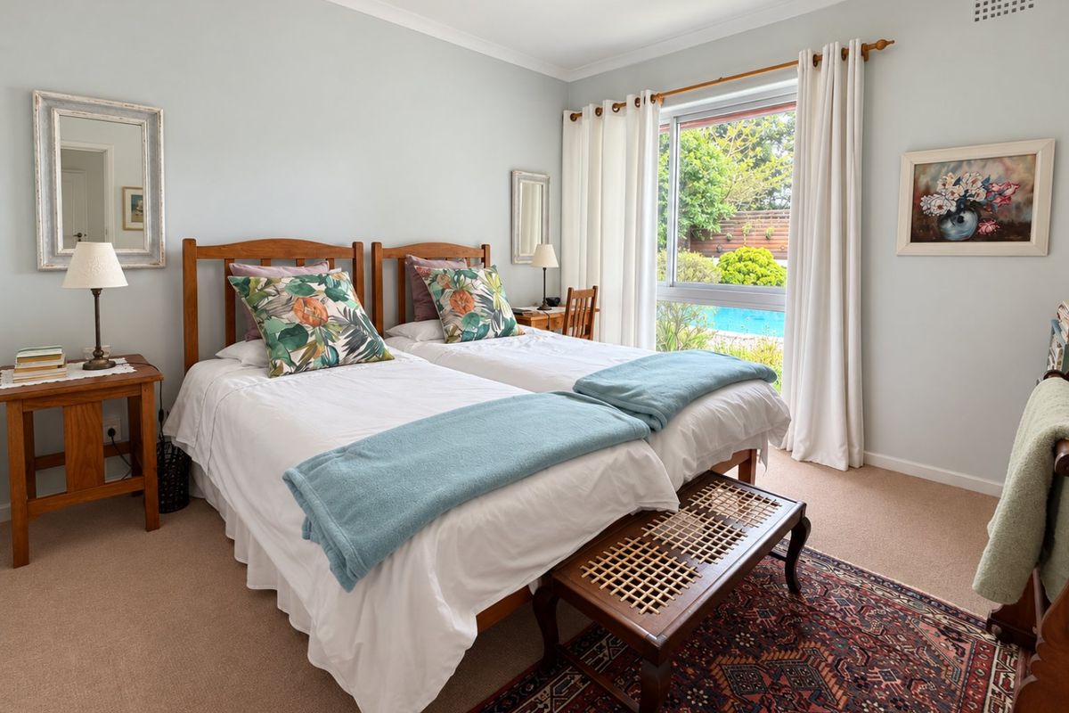 A well-maintained bedroom featuring neutral wall tones, carpet flooring, and a large sliding window providing natural light and views of the pool area.