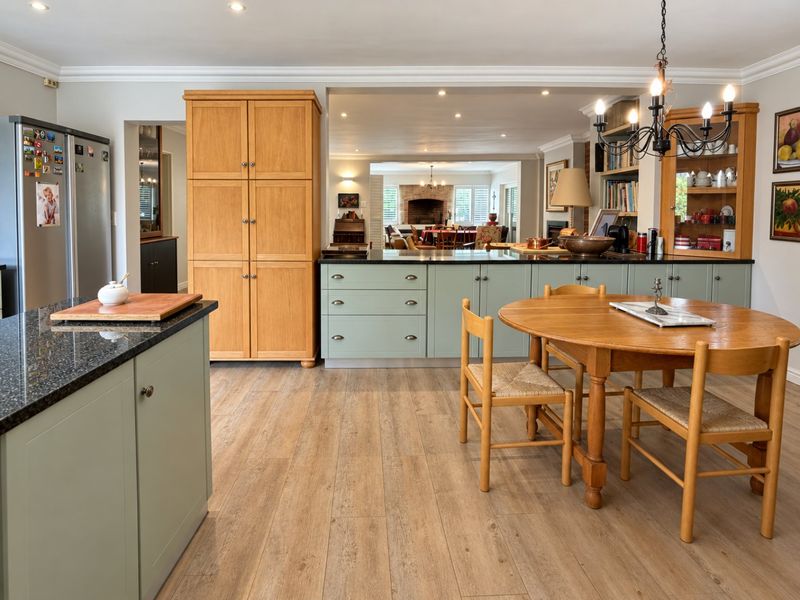 Spacious open-plan kitchen and dining area featuring custom cabinetry, granite countertops, and warm wood-look flooring, seamlessly flowing into the adjacent living space.