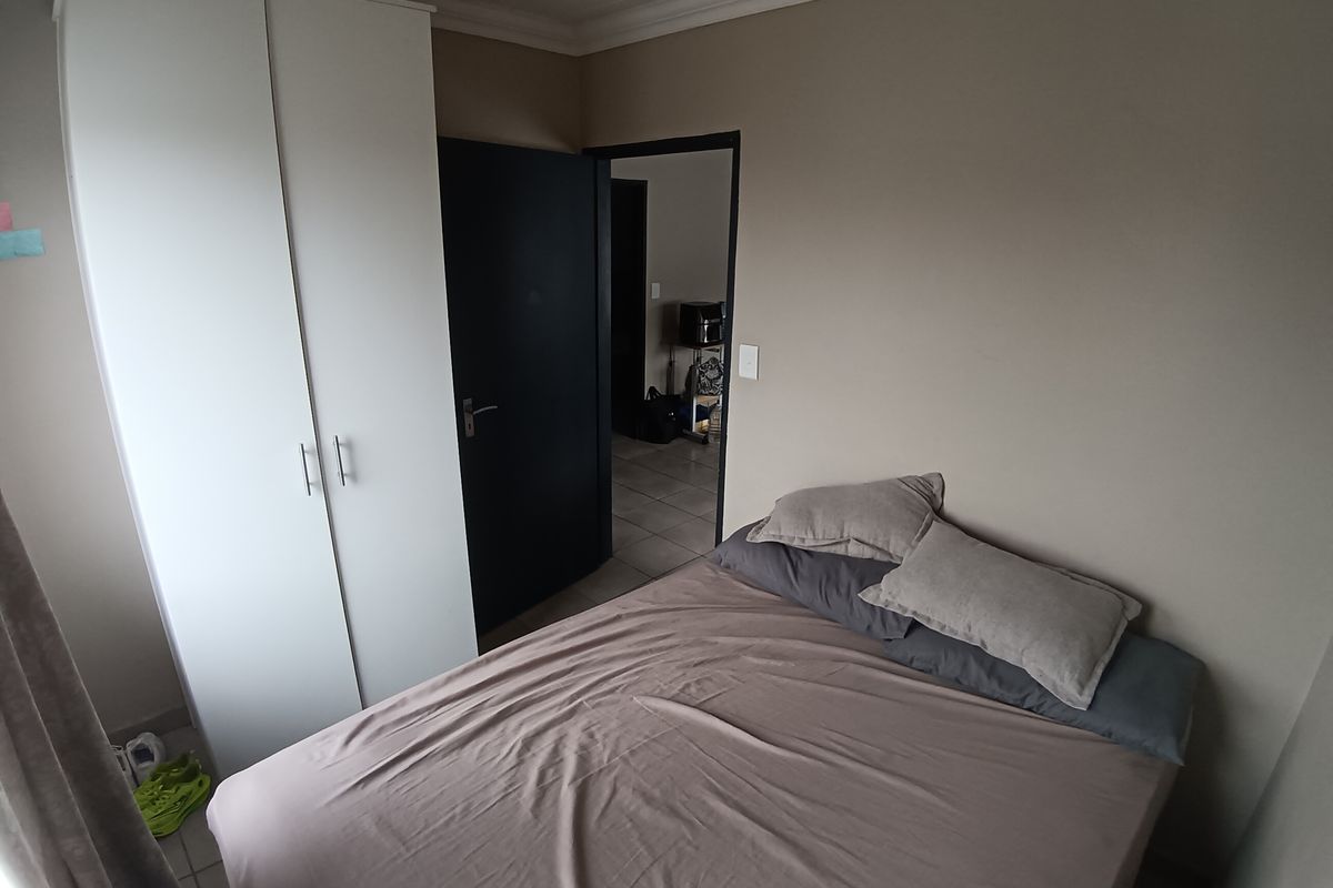 A compact bedroom featuring tiled flooring, a built-in wardrobe, and neutral wall tones, providing a functional living space.