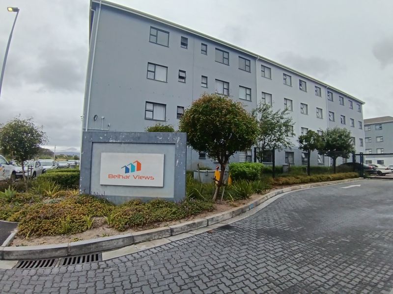 Exterior view of the Belhar Views apartment complex, featuring a paved entrance, landscaped garden, and clear signage for the residential property.