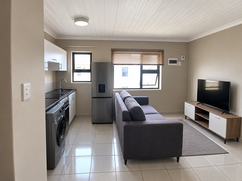 Modern open-plan living area featuring a compact kitchen with built-in cabinetry, tiled flooring, and a bright, neutral aesthetic throughout.