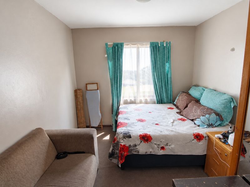 A functional bedroom featuring carpeted flooring and a window with curtains, providing a neutral space ready for personalization.