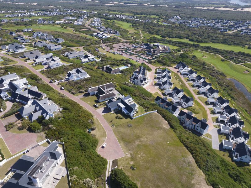 An aerial view of a residential townhouse estate featuring well-maintained properties, paved roads, and surrounding natural landscape.