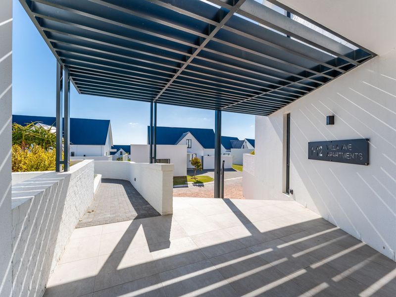 Modern entrance area featuring a sleek metal pergola, tiled flooring, and clear signage for the Villa Ave Apartments complex.