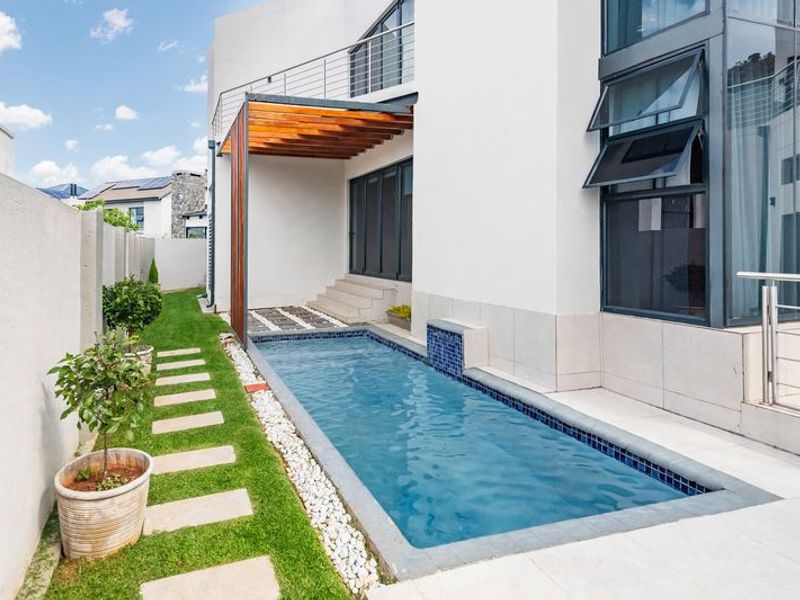 Modern outdoor area featuring a sleek lap pool, timber pergola, and tiled patio, seamlessly integrated with the contemporary architectural design of the home.