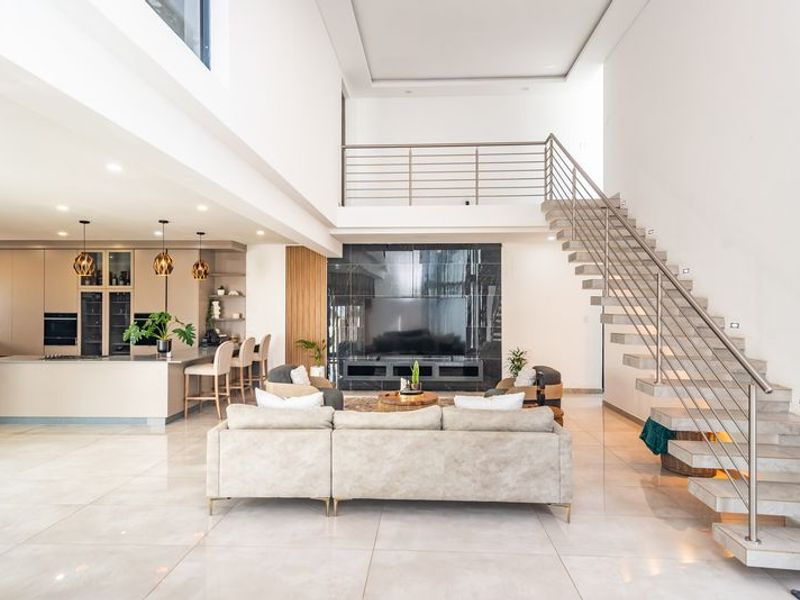 Spacious open-plan living area featuring a modern kitchen with integrated appliances, a striking floating staircase, and high-end finishes throughout.