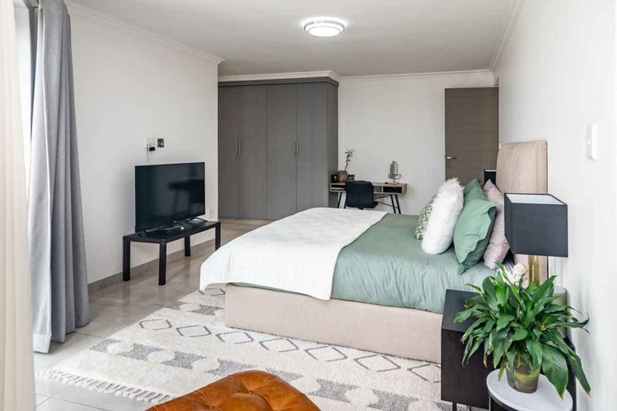 A well-maintained bedroom featuring neutral walls, tiled flooring, and ample built-in cupboard storage space.