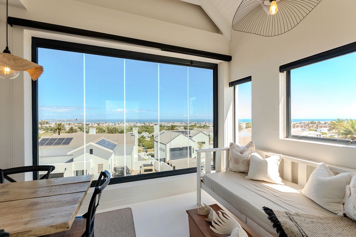 Bright living area featuring a vaulted ceiling and expansive glass sliding doors offering panoramic coastal views.