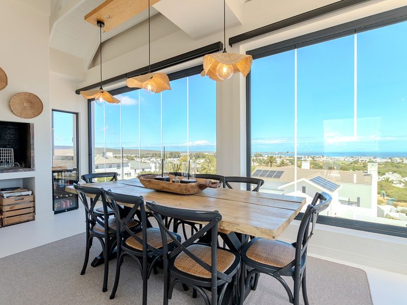 Bright dining area featuring a built-in fireplace, integrated wine cooler, and expansive glass doors offering panoramic coastal views.