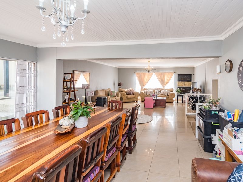 Spacious open-plan living and dining area featuring tiled flooring, a tongue and groove ceiling, and large sliding glass doors leading to the exterior.