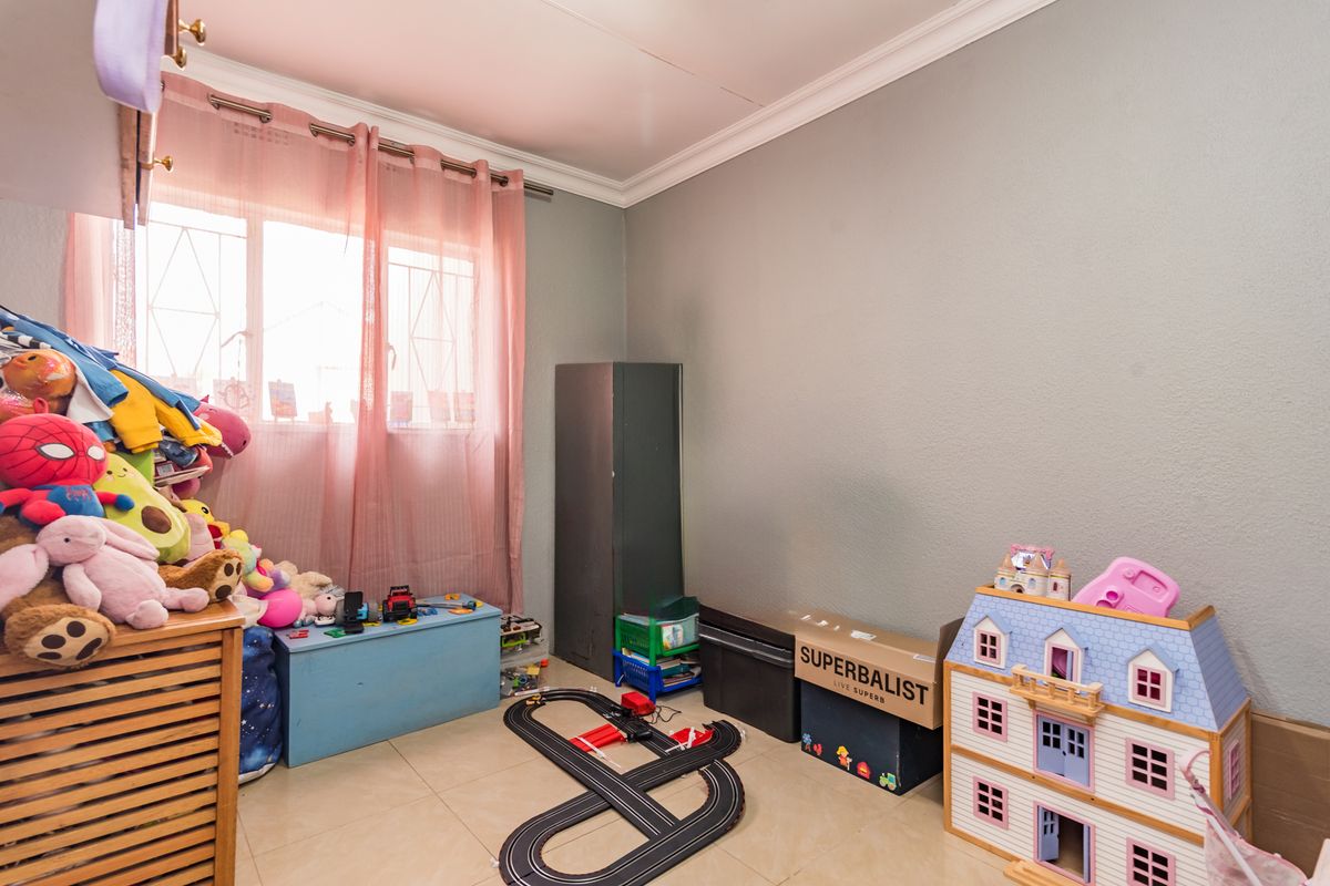 A bedroom featuring tiled flooring, neutral wall paint, and a window fitted with security bars.