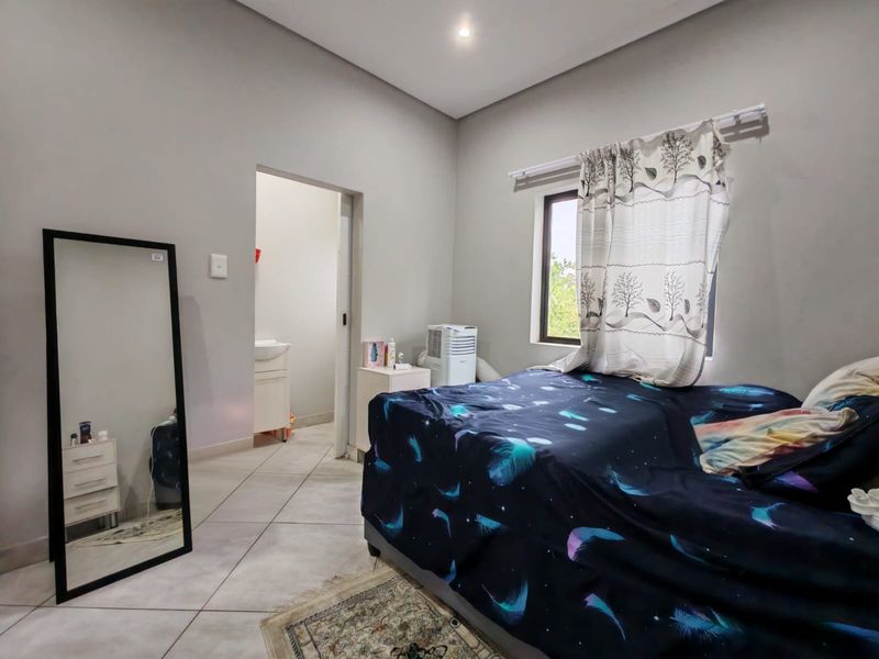 A functional bedroom featuring tiled flooring, recessed ceiling lights, and an adjoining en-suite bathroom, offering a neutral base for personalization.