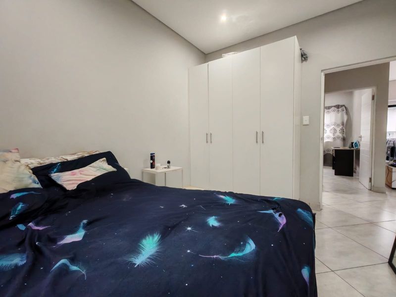 A well-maintained bedroom featuring neutral wall tones, tiled flooring, and ample built-in cupboard storage space.