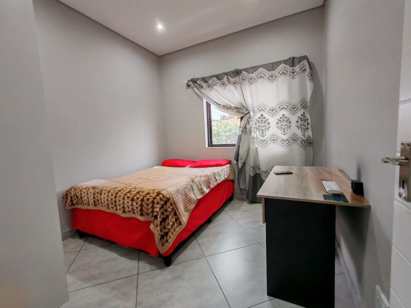 A well-maintained bedroom featuring neutral wall tones, tiled flooring, and recessed ceiling lighting, providing a clean and functional living space.