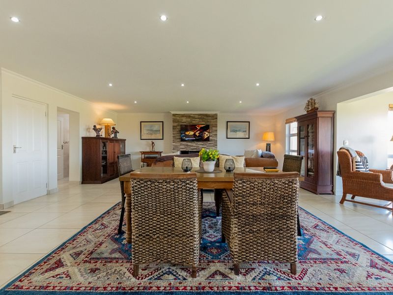 Spacious open-plan living and dining area featuring tiled flooring, recessed lighting, and a central stone-clad fireplace.