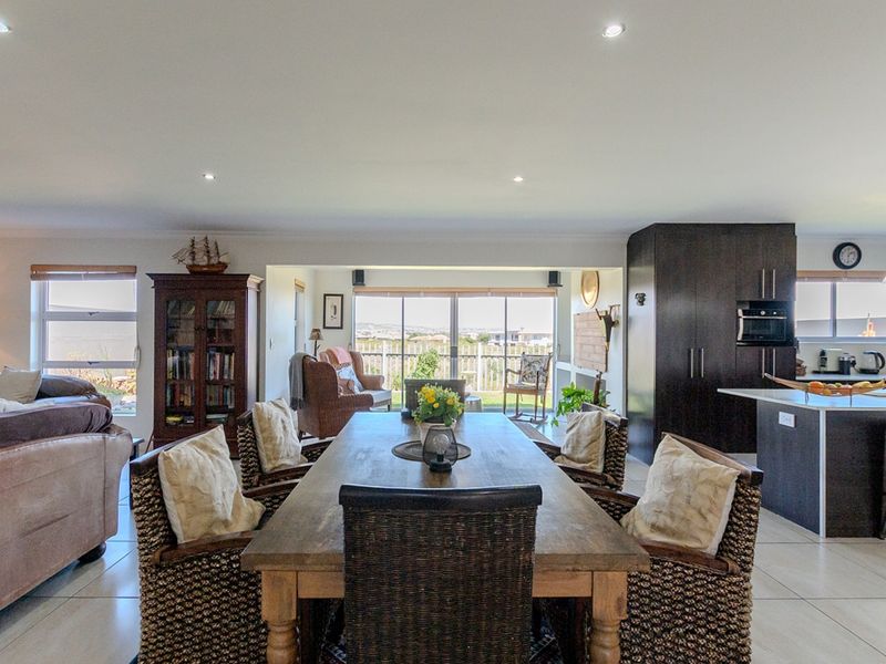Spacious open-plan living, dining, and kitchen area featuring modern tiled floors, recessed lighting, and a functional kitchen island with built-in appliances.