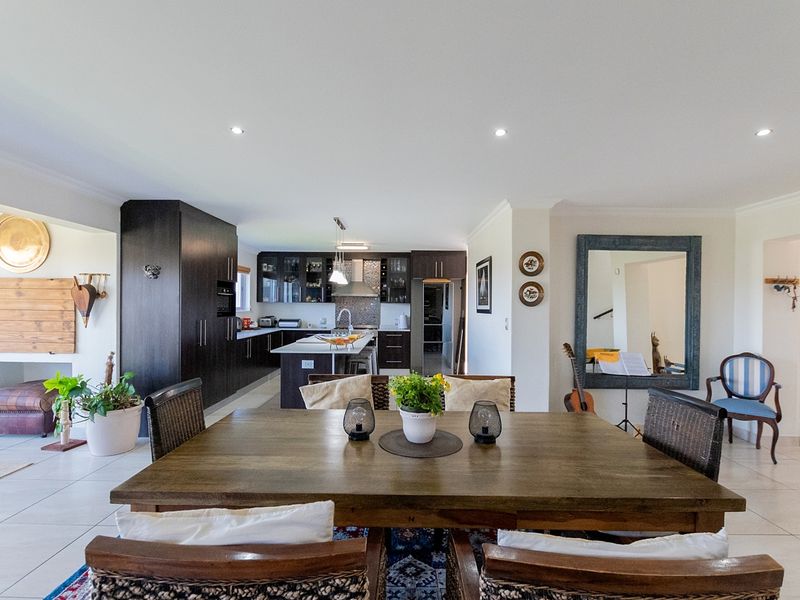 Spacious open-plan living and dining area featuring a modern kitchen with dark cabinetry, a central island, and tiled flooring throughout.