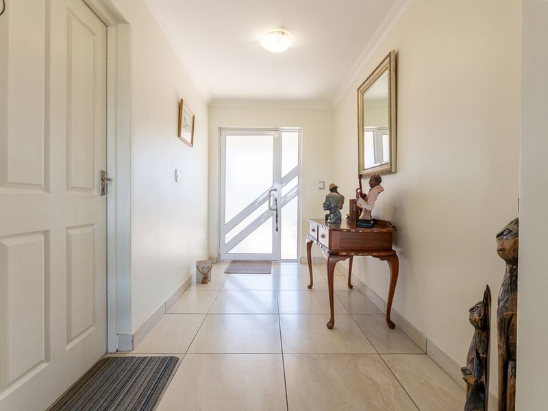 A bright and welcoming entrance hall featuring neutral tiled flooring and a modern frosted glass front door.
