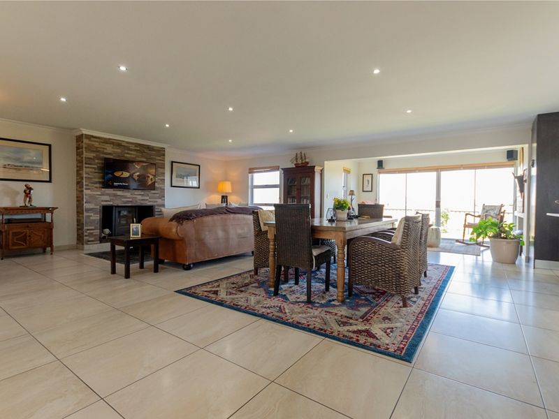 Spacious open-plan living and dining area featuring large format floor tiles, a stone-clad fireplace, and sliding glass doors leading to an outdoor space.