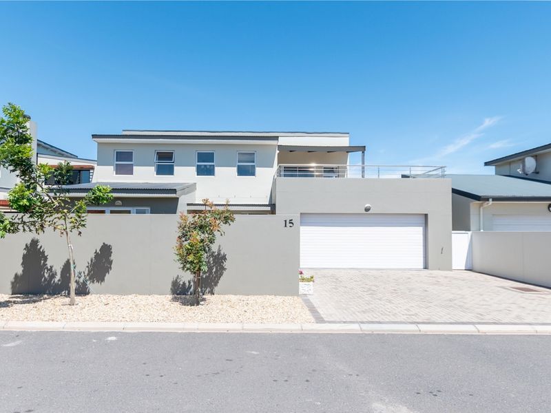 Modern double-story residential property featuring a paved driveway, secure double garage, and an upper-level balcony with metal railings.
