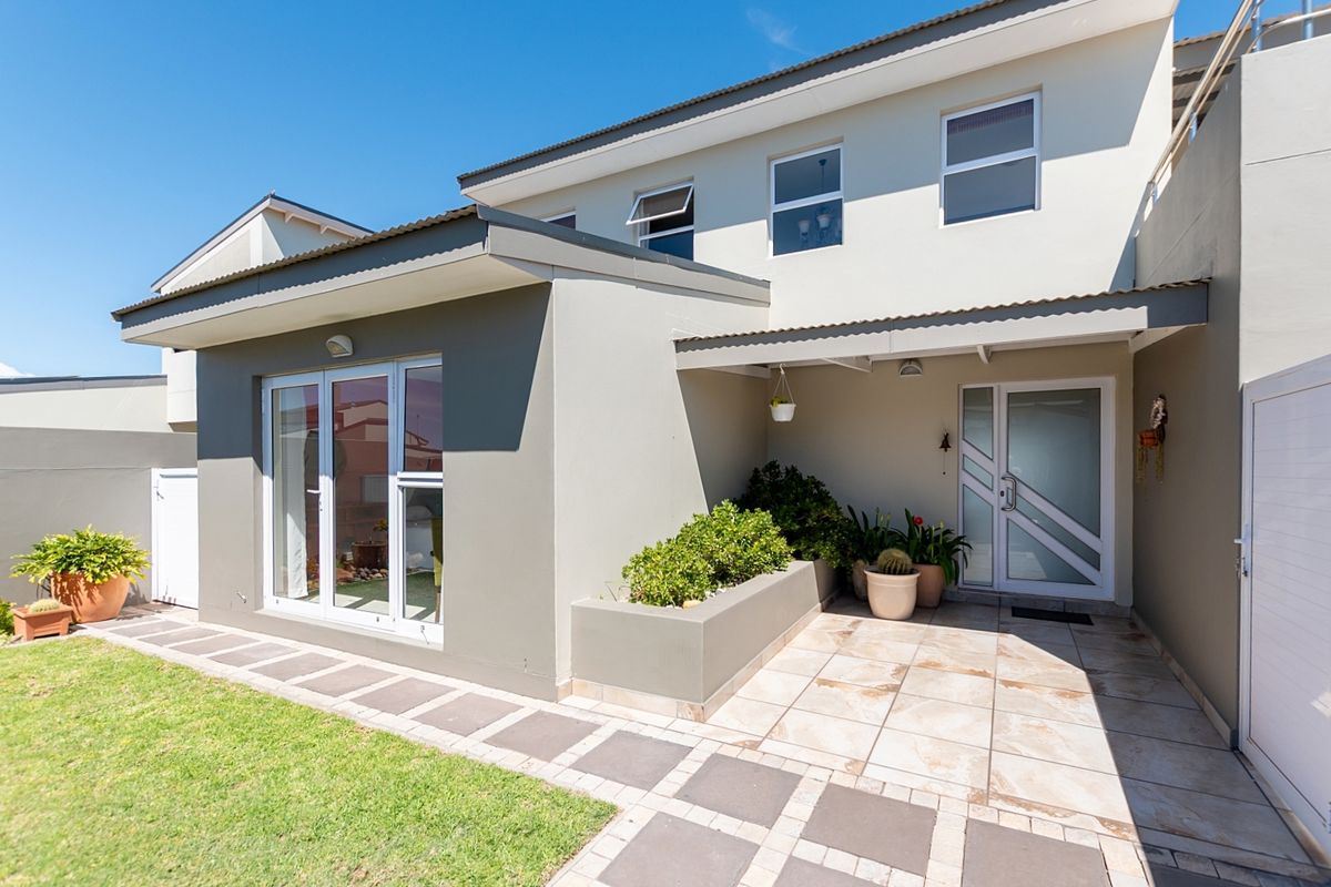 A well-maintained rear exterior featuring a tiled patio, built-in planter box, and modern sliding glass doors leading into the home.