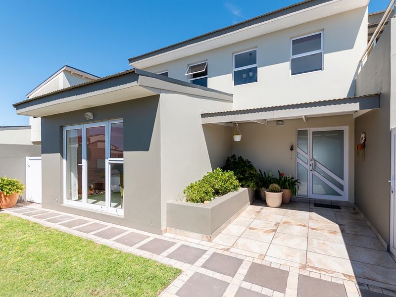 A well-maintained rear exterior featuring a tiled patio, built-in planter box, and modern sliding glass doors leading into the home.