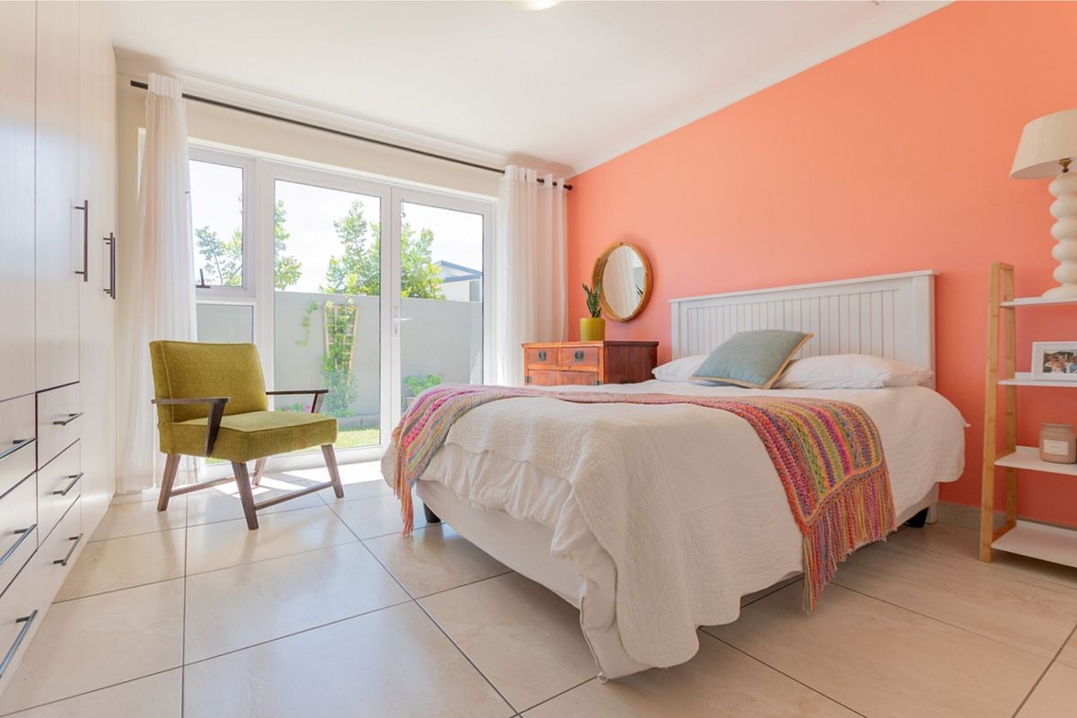 Bright bedroom featuring tiled flooring, built-in cupboards, and sliding glass doors providing direct access to the outdoor area.