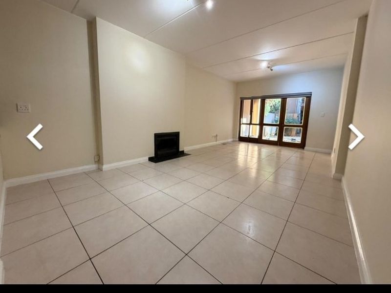 Spacious, empty living room featuring neutral tiled flooring, a built-in fireplace, and large sliding glass doors providing access to the exterior.