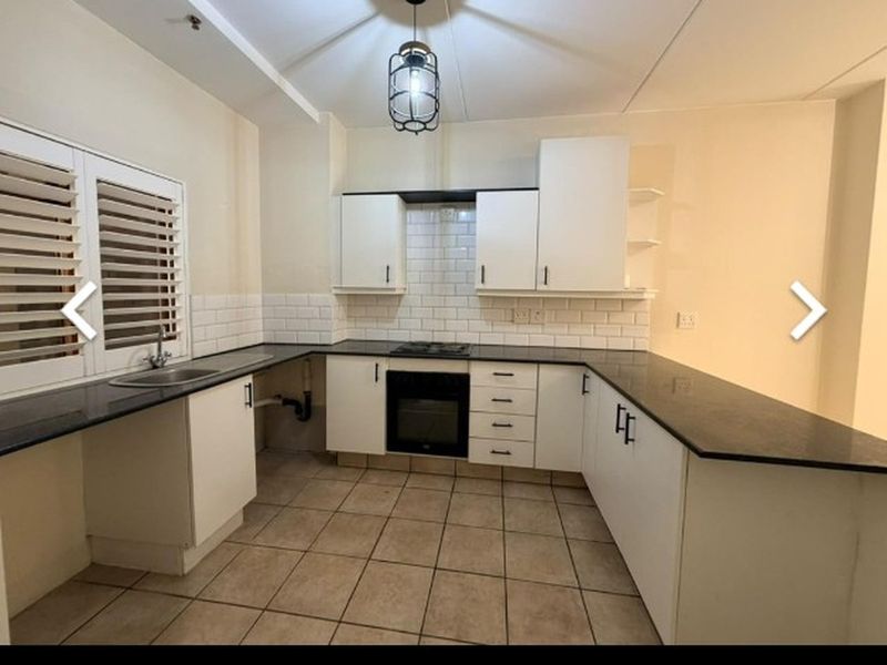 A functional kitchen featuring white cabinetry, dark stone countertops, subway tile backsplash, and integrated appliances, ready for minor cosmetic updates.