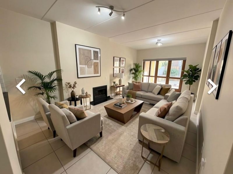 A well-lit living room featuring a built-in fireplace, neutral tiled flooring, and large windows that provide natural light.