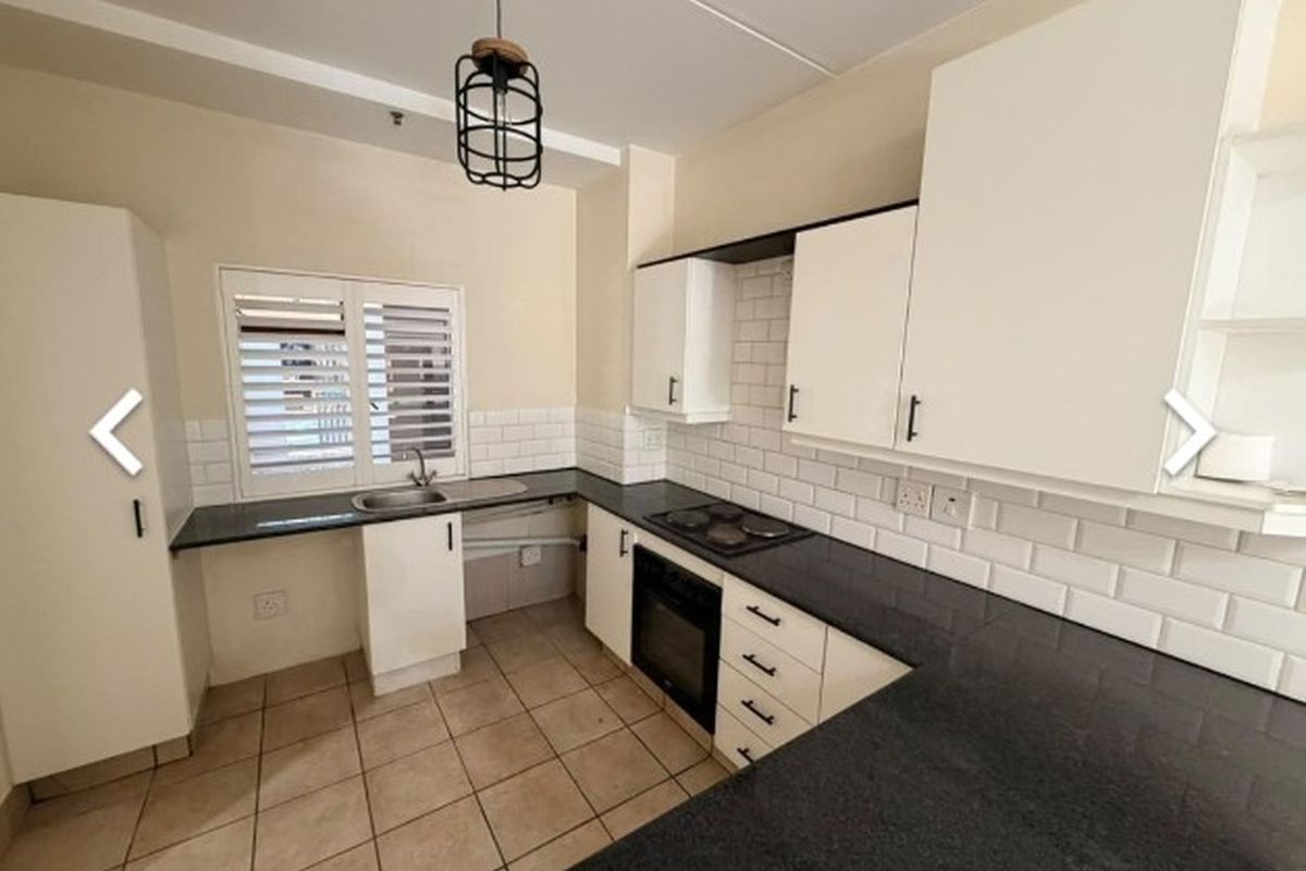 A clean, functional kitchen featuring white cabinetry, dark granite countertops, subway tile backsplash, and integrated appliances including an oven and hob.