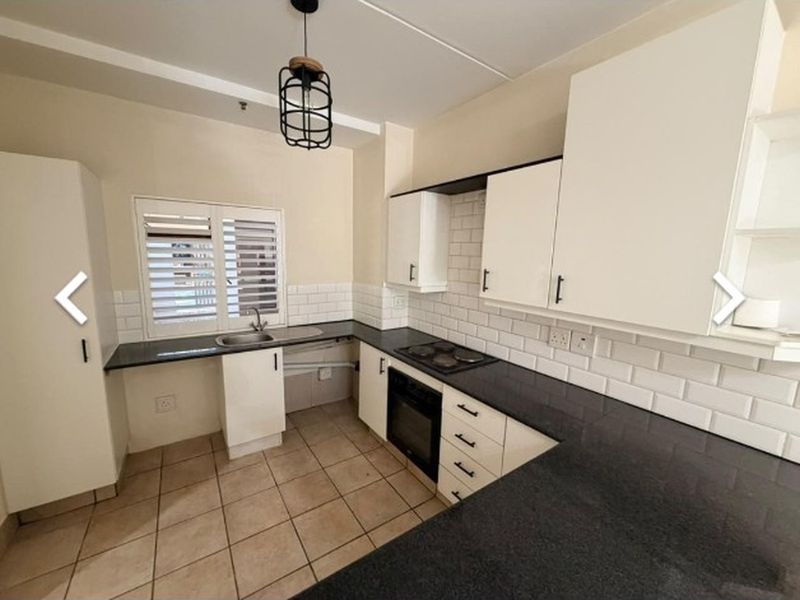 A clean, functional kitchen featuring white cabinetry, dark granite countertops, subway tile backsplash, and integrated appliances including an oven and hob.