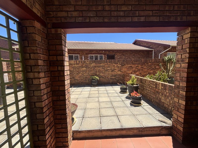 A private paved patio area enclosed by brick walls, offering a low-maintenance outdoor space suitable for relaxation.