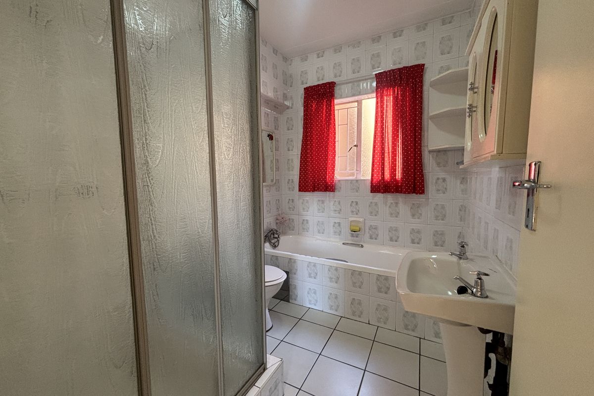 A dated bathroom featuring a shower enclosure, bathtub, pedestal basin, and toilet with original wall and floor tiling.