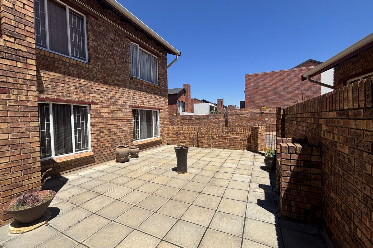 A private rear courtyard featuring face brick walls and paved flooring, providing a low-maintenance outdoor space for the townhouse.