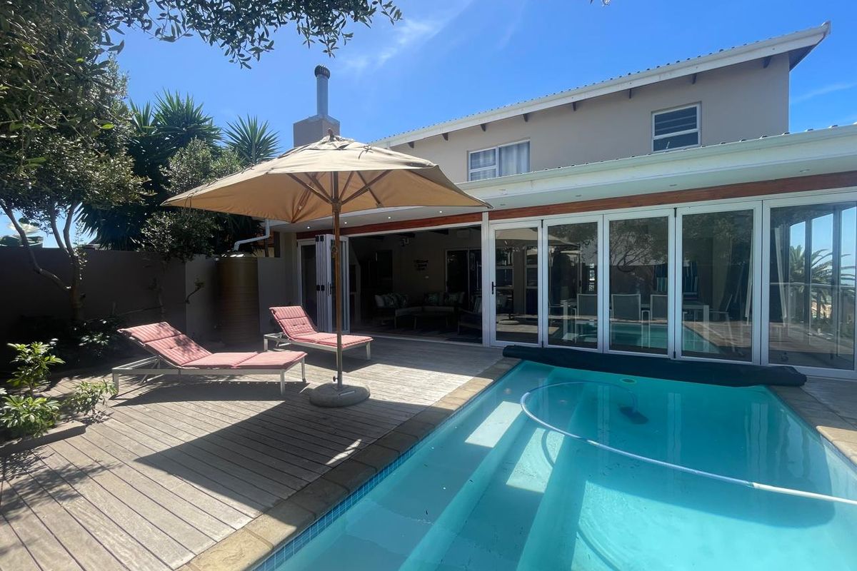 Rear exterior view featuring a swimming pool, timber decking, and large bi-fold doors providing seamless indoor-outdoor flow to the townhouse living area.